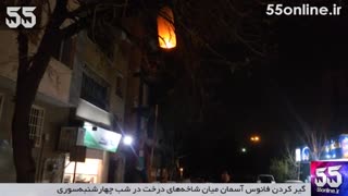 گیر کردن فانوس آسمان میان شاخه‌های درخت در شب چهارشنبه‌سوری